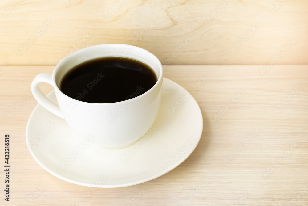 A white coffee cup sits on a wooden surface.