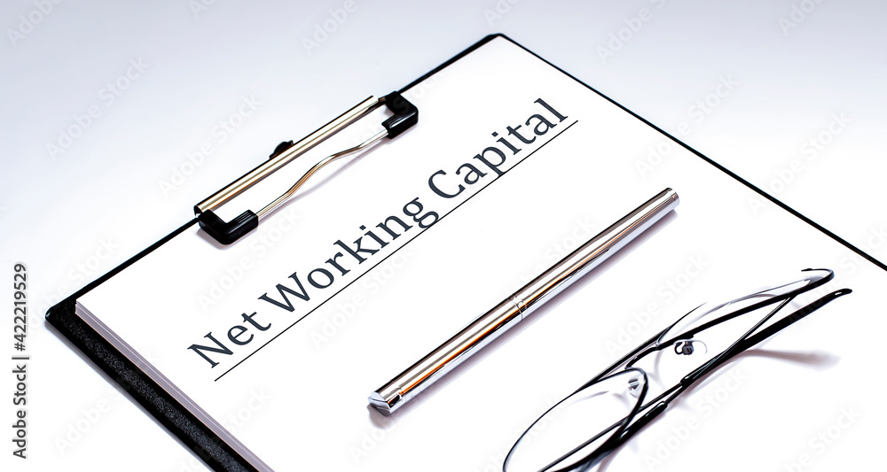 Naklejka premium Paper with Net Working Capital on a table with glasses and pen