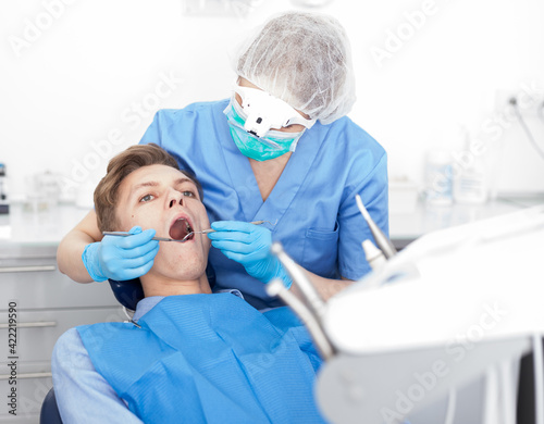 Dentist female in uniform is examinating of male in dental clinic. High quality photo
