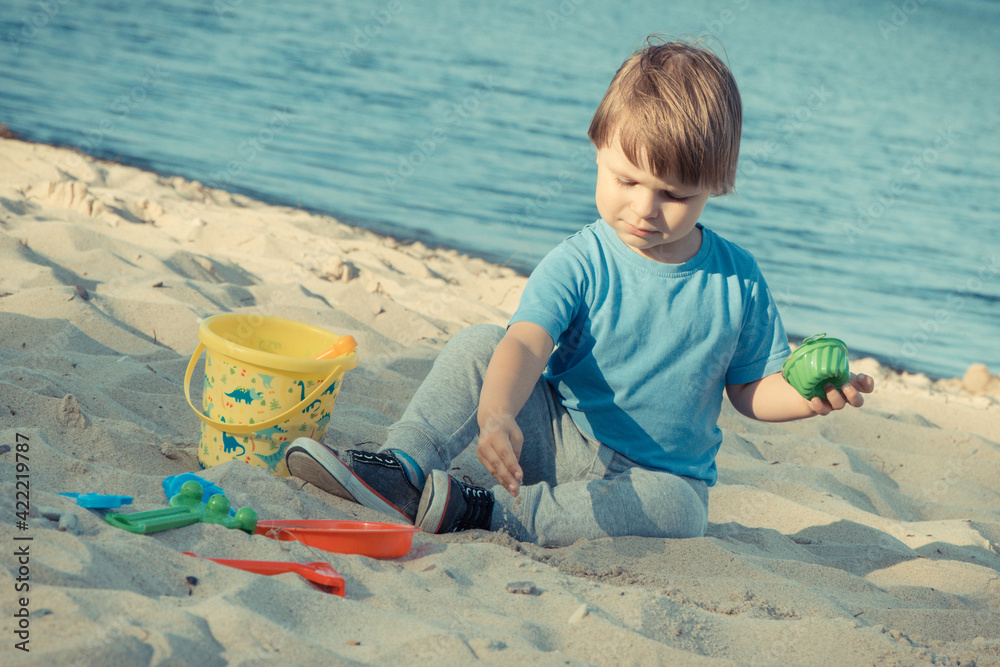 Baby boy playing with sand on summer beach. Vacation time and child development concept Baby boy playing with sand on summer beach. Vacation time and child development concept