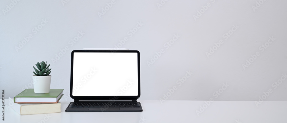 Minimal workplace with computer tablet, books, plant and copy space on white table. Minimal workplace with computer tablet, books, plant and copy space on white table.