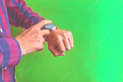 Man with smart watch on green background. Concept for business, multi payment, lifestyle using. Smartwatch - modern digital gadget with empty display, copy space. © Konstantin Savusia