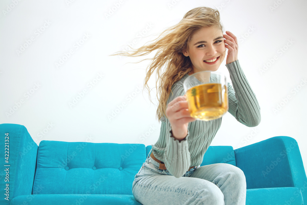 Young woman sitting at home and drinking tea, interior. High quality photo.