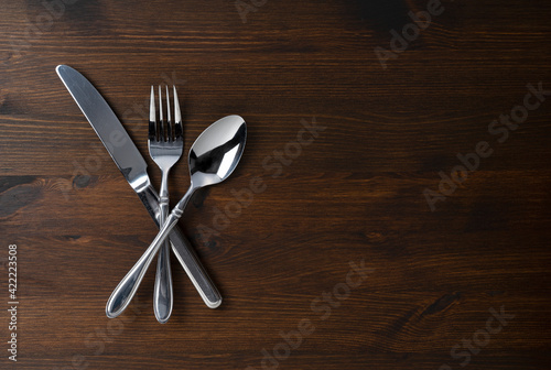 Spoon, fork, and knife on a wooden table.