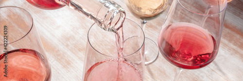 Pouring rose wine panorama with various wineglasses