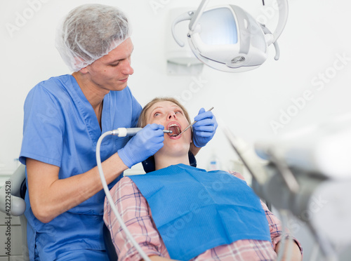 Male dentist treating young female patient in dental office. High quality photo