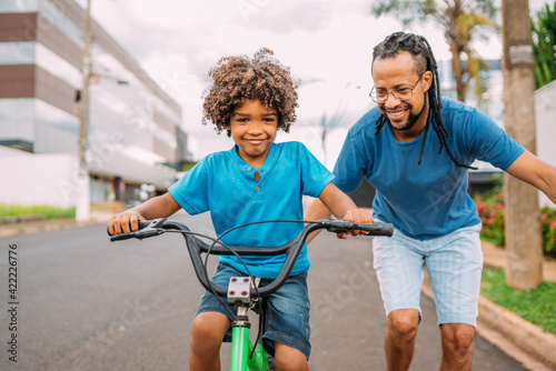 latinx father is teaching her son to ride the bike photo