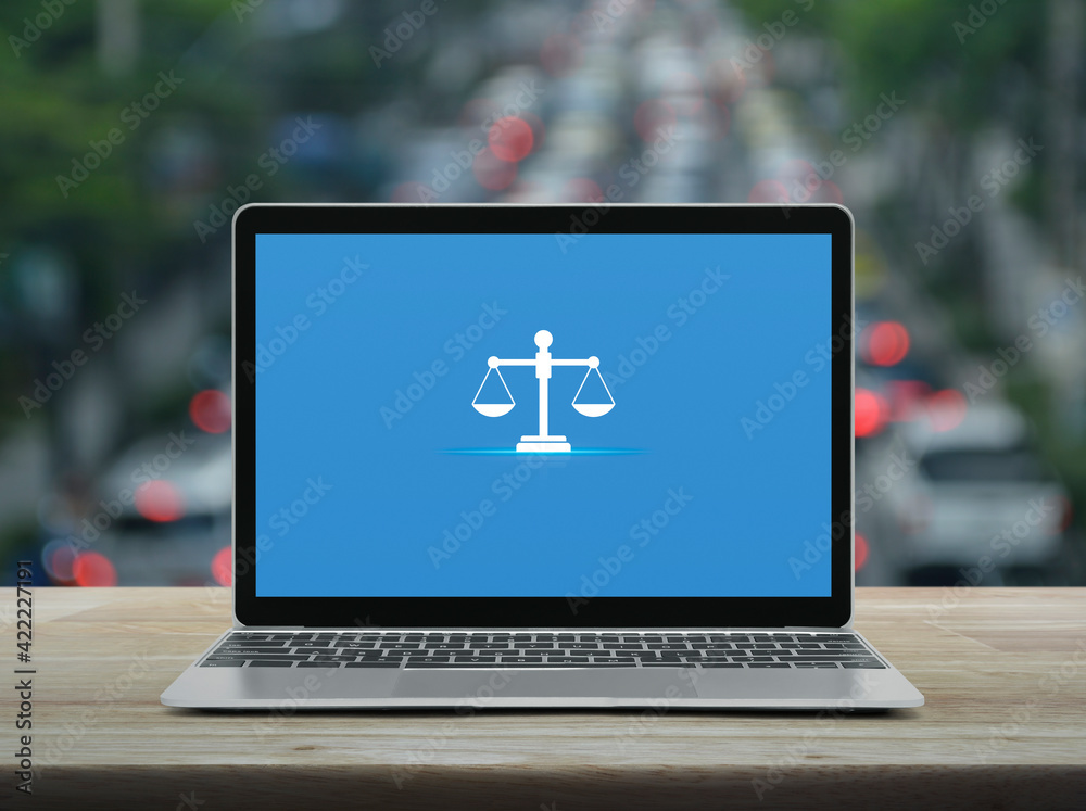 Law flat icon with modern laptop computer on wooden table over blur of rush hour with cars and road in city, Business legal service online concept Law flat icon with modern laptop computer on wooden table over blur of rush hour with cars and road in city, Business legal service online concept