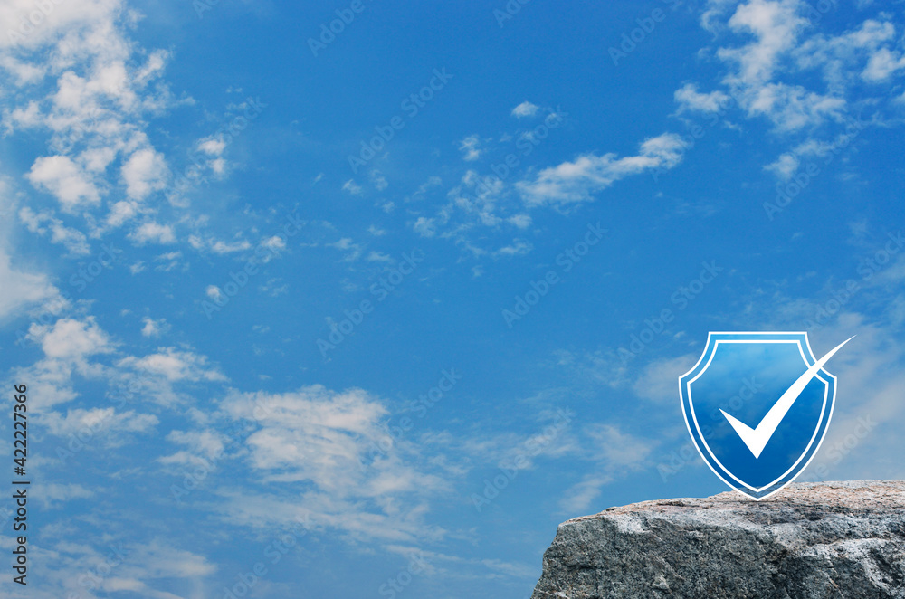 Security shield with check mark flat icon on rock mountain over blue sky with white clouds, Technology internet cyber security and anti virus concept Security shield with check mark flat icon on rock mountain over blue sky with white clouds, Technology internet cyber security and anti virus concept