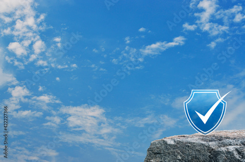 Security shield with check mark flat icon on rock mountain over blue sky with white clouds, Technology internet cyber security and anti virus concept