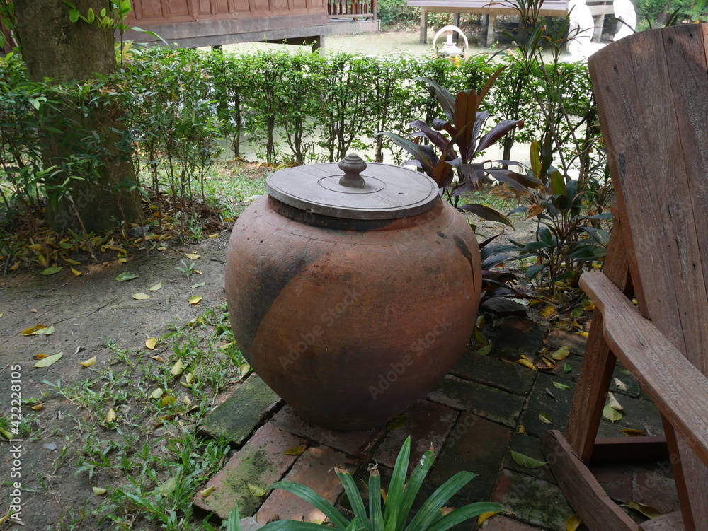 Traditional Thai design of big water jar (vat) with the cap in the garden. Ancient handmade container concept. Traditional Thai design of big water jar (vat) with the cap in the garden. Ancient handmade container concept.