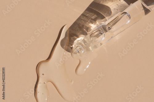 close up of pipette with pouring liquid serum and shadows photo