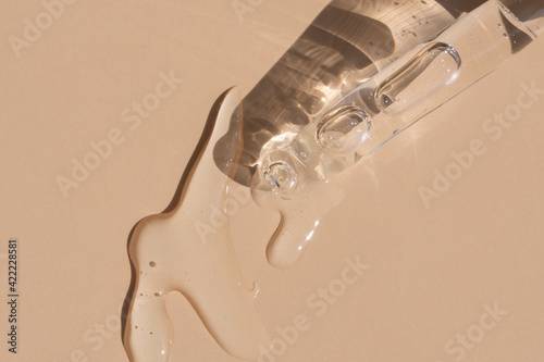 close up of pipette with pouring liquid serum and shadows