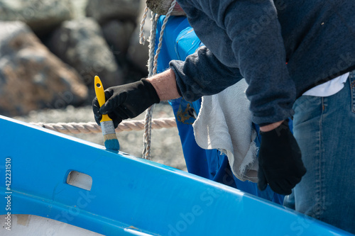 a man painting a boat with blue paint