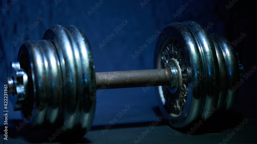 Chrome Iron dumbbells on a blue dark energetic background Chrome Iron dumbbells on a blue dark energetic background