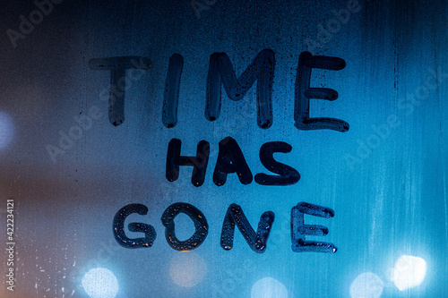 the words time has gone handwritten on night wet window glass surface photo