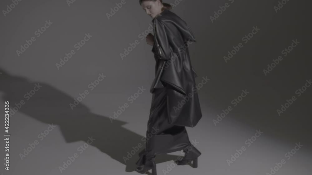 Dark hair woman posing in the black dress in the studio lights. Young attractive woman wearing a black dress. Ungraded video. Dark hair woman posing in the black dress in the studio lights. Young attractive woman wearing a black dress. Ungraded video.