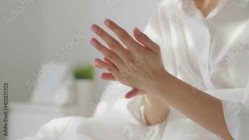 Close up of woman hand holding and applying moisturiser, Body lotion in bedroom.