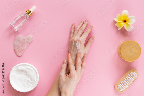 Skin care  female hands with cream  gua sha  oil on a pink background. Horizontal orientation  top view.