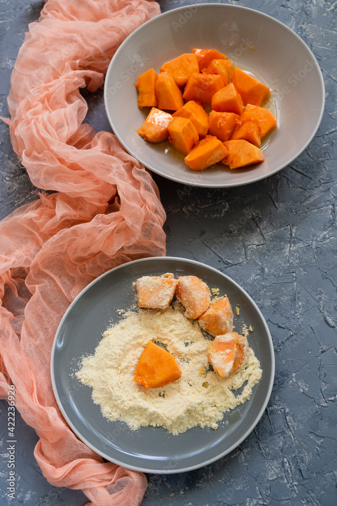 Ripe pumpkin in corn flour before sending to a preheated pan Ripe pumpkin in corn flour before sending to a preheated pan