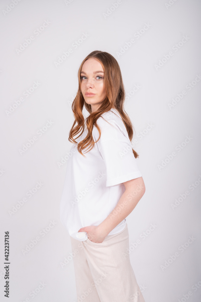 Cozy lifestyle concept. Portrait of young beautiful redhead woman in white t-shirt and beige pants. Cozy lifestyle concept. Portrait of young beautiful redhead woman in white t-shirt and beige pants.