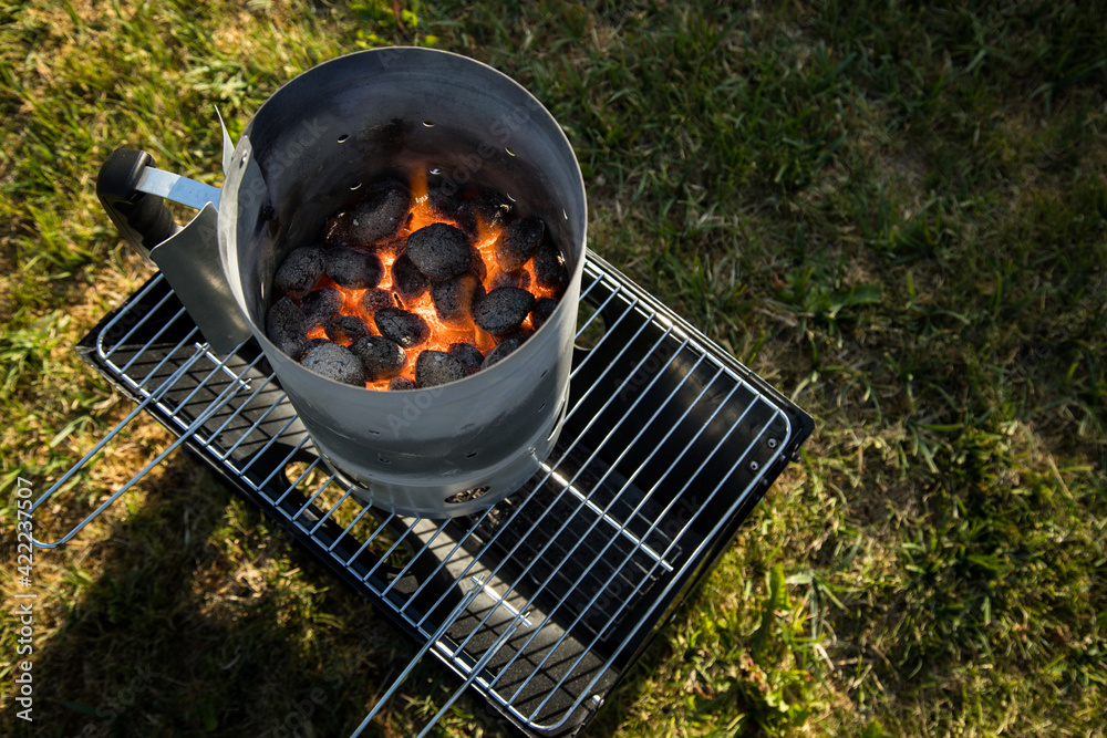 Kohle von Holzkohlegrill brennt mit Feuer und Anzünder im Anzündkamin zum  Anheizen für Grill Stock Photo | Adobe Stock