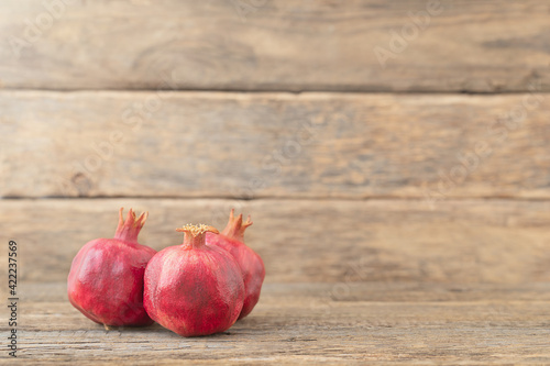 Three whole ripe pomegranates lying on wooden background