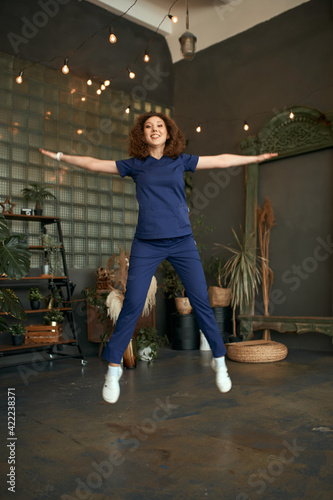 The girl doctor jumps happy. young female doctor in blue surgical suit.