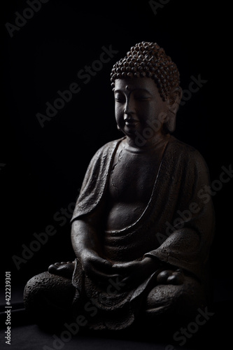 Meditating Buddha Statue isolated on black background. 