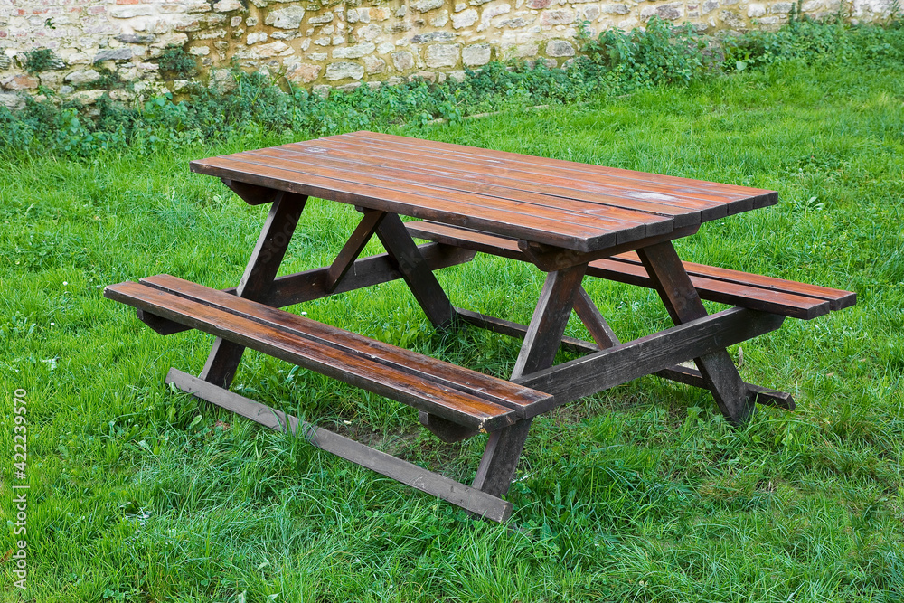 Wooden empty picnic table on a green meadow of a public park Wooden empty picnic table on a green meadow of a public park