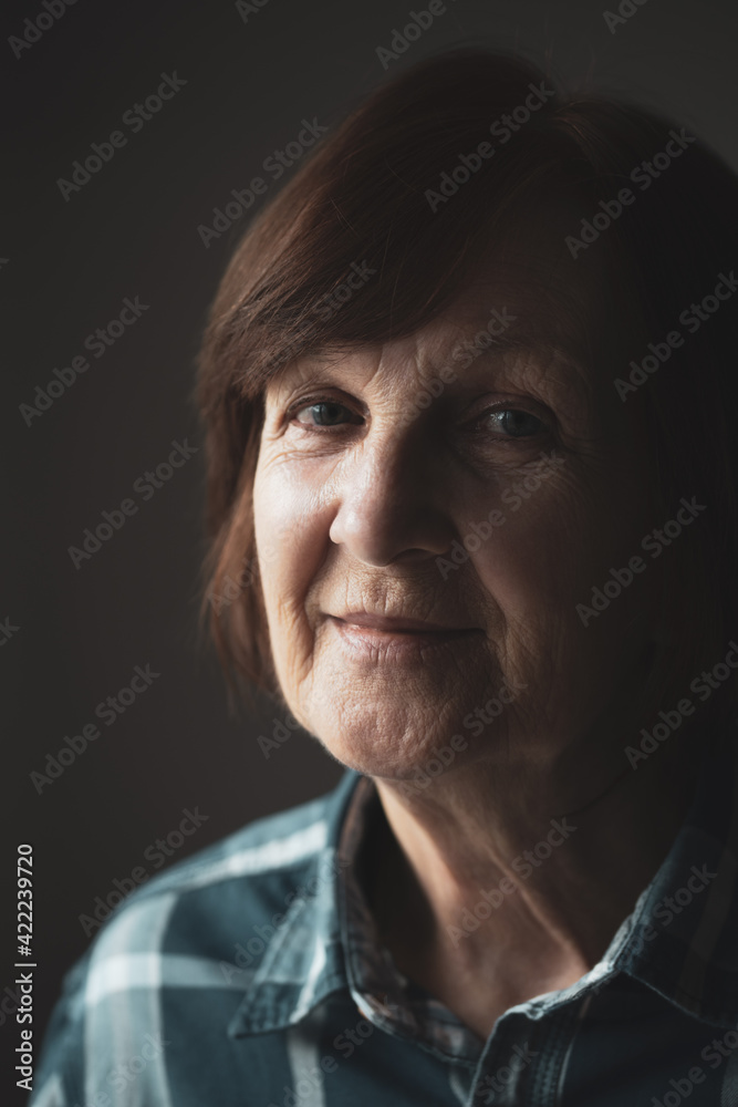 Close-up portrait of senior woman with wrinkled skin on face.