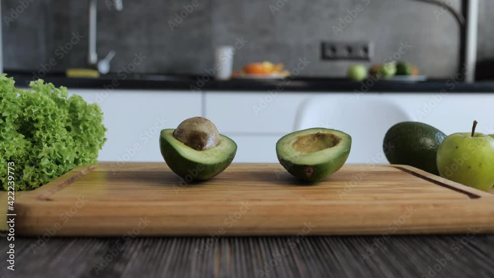 Woman s hands holding avocado cut in two half of kitchen background