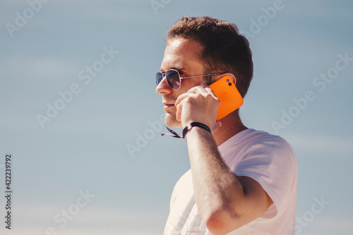 man with sunglasses walking on the beach and talking on the phone © tetxu