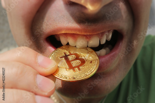 Foto The young man bites bitcoin. Check bitcoin for strength.