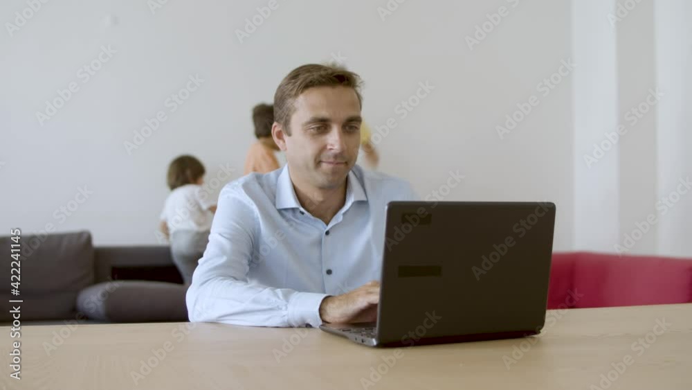 Caucasian middle-aged father working at home when cute children playing on sofa. Exited lovely girl looking at laptop screen and hugging dad. Slider motion. Fatherhood and digital technology concept Caucasian middle-aged father working at home when cute children playing on sofa. Exited lovely girl looking at laptop screen and hugging dad. Slider motion. Fatherhood and digital technology concept