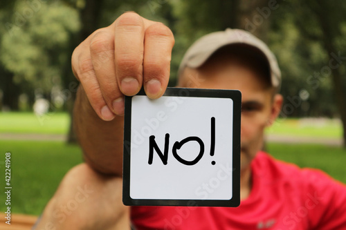 A man in a cap holds a sign with the inscription 