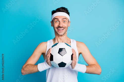 Photo of amazed soccer player catch football wear white singlet isolated over blue color background © deagreez