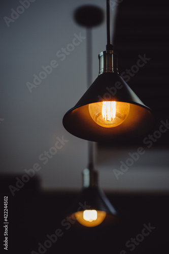 Black retro chandelier with metal details hanging on the cable. Incandescent lamp. Scattered focus. Edison's lamp