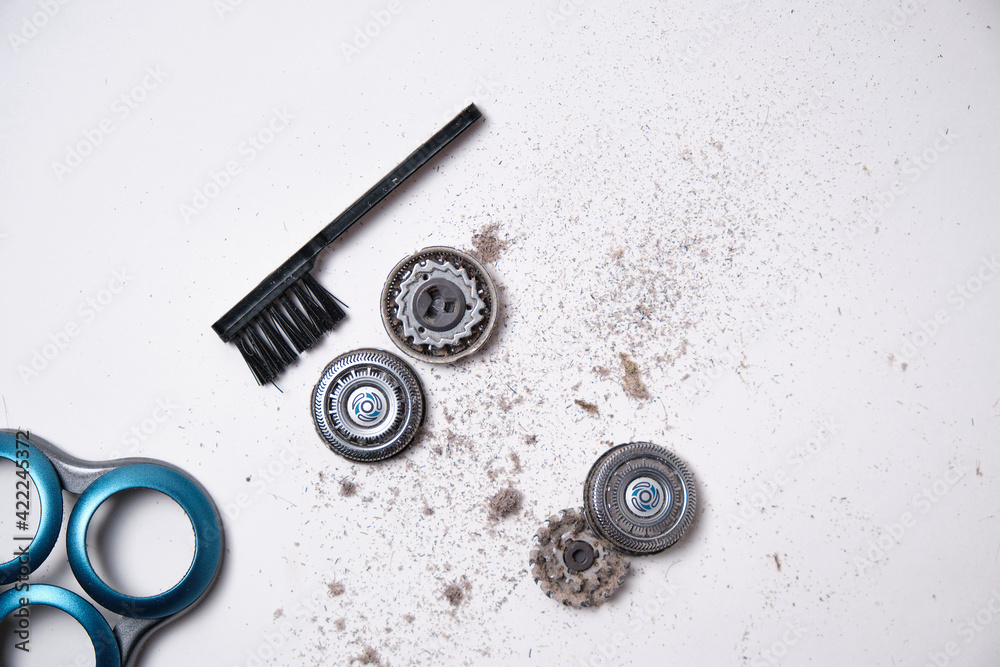 Details of a disassembled dirty shaver head and a cleaning brush on a light background. Soft selective focus. Copy space Details of a disassembled dirty shaver head and a cleaning brush on a light background. Soft selective focus. Copy space