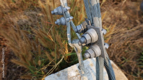 Bolt fixed on guy wire. U-BOLT or clamp with bolt attached to the metal anchor on the concrete base to support the tension of electric pole with copy area. Selective focus