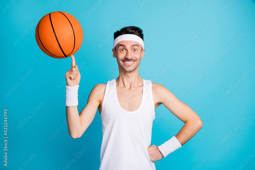 Photo of young excited cheerful sportive man happy smile spin ball on finger isolated over blue color background