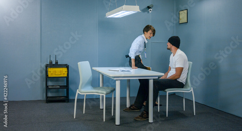 Angry detective woman in interrogation room screams at suspect. © Maxim