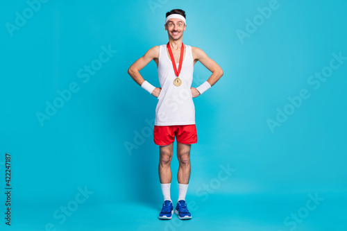 Full body photo of positive man put hands on waist golden medal hang on neck isolated on blue color background © deagreez