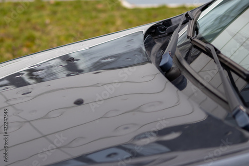 Car engine hood with many hail damage dents show the forces of nature and the importance of car insurance and a replacement value insurance against hail storm and storm hazards or extreme weather