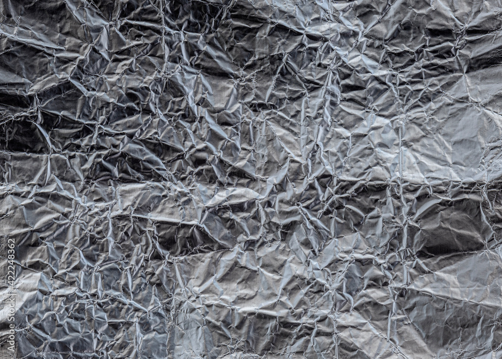 Wrinkled metal foil texture, silver color, grunge abstract background.