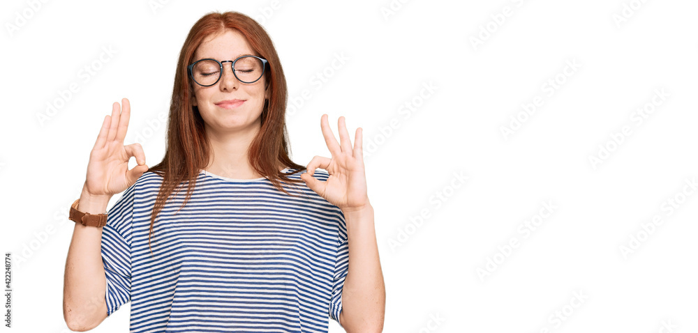 Young read head woman wearing casual clothes and glasses relaxed and smiling with eyes closed doing meditation gesture with fingers. yoga concept. Young read head woman wearing casual clothes and glasses relaxed and smiling with eyes closed doing meditation gesture with fingers. yoga concept.