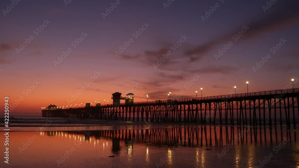Pier silhouette Oceanside California USA. Pacific ocean tide tropical beach. Summertime gloaming atmosphere. Purple aesthetic gradient, calm twilight sky, pink violet dusk. Lights reflection in water. Pier silhouette Oceanside California USA. Pacific ocean tide tropical beach. Summertime gloaming atmosphere. Purple aesthetic gradient, calm twilight sky, pink violet dusk. Lights reflection in water.