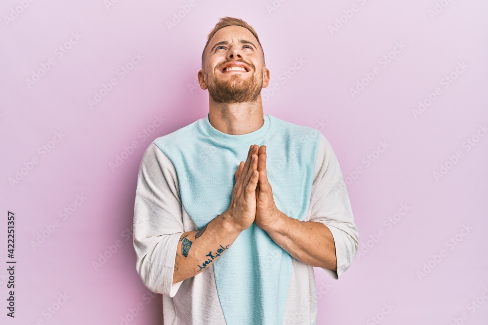 Young caucasian man wearing casual clothes begging and praying with hands together with hope expression on face very emotional and worried. begging. Young caucasian man wearing casual clothes begging and praying with hands together with hope expression on face very emotional and worried. begging.