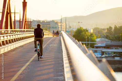Person riding a bicycle on a bridge sidewalk