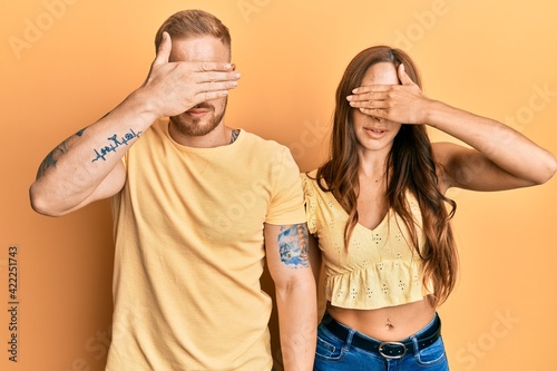 Young couple of girlfriend and boyfriend hugging and standing together covering eyes with hand, looking serious and sad. sightless, hiding and rejection concept